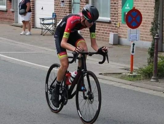 Xander racing through a town in red and black team kit.