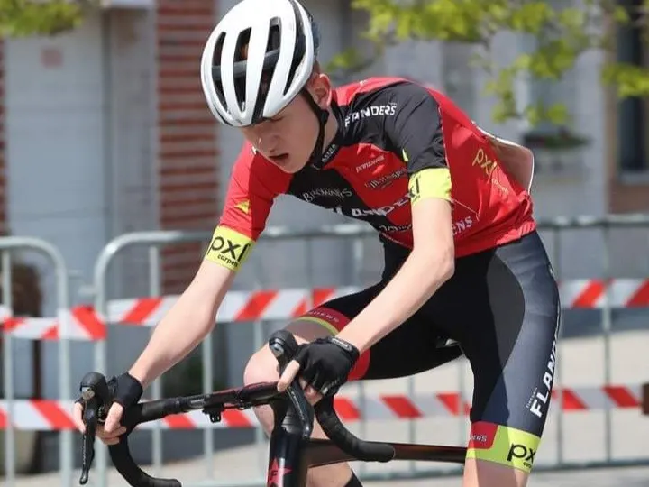 Xander racing in red and black Flanders team kit, head down over the handlebars.