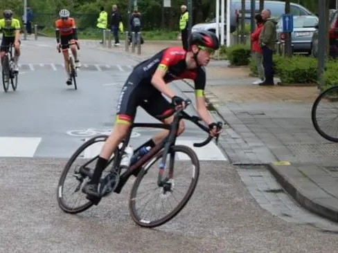 Xander cornering in a junior race in red and black team kit.